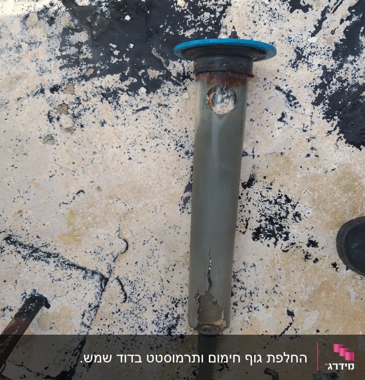 צינור מתכת חלוד עם חור על רקע רצפה